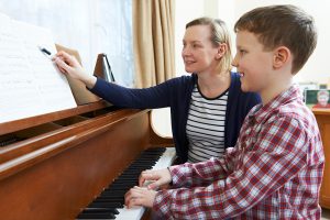 Boy With Piano Teacher Having Lesson At Piano