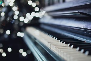Closeup of used grand piano with lights twinkling in background