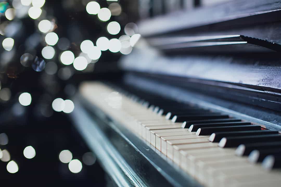 Closeup of used grand piano with lights twinkling in background Closeup of used grand piano with lights twinkling in background