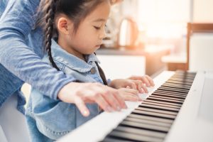 Girl playing piano parents bought using piano buying guide