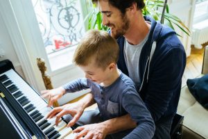 Father and son playing baby grand piano