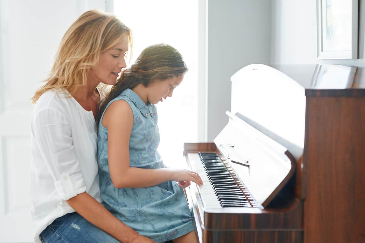 Mother and daughter playing affordable upright piano
