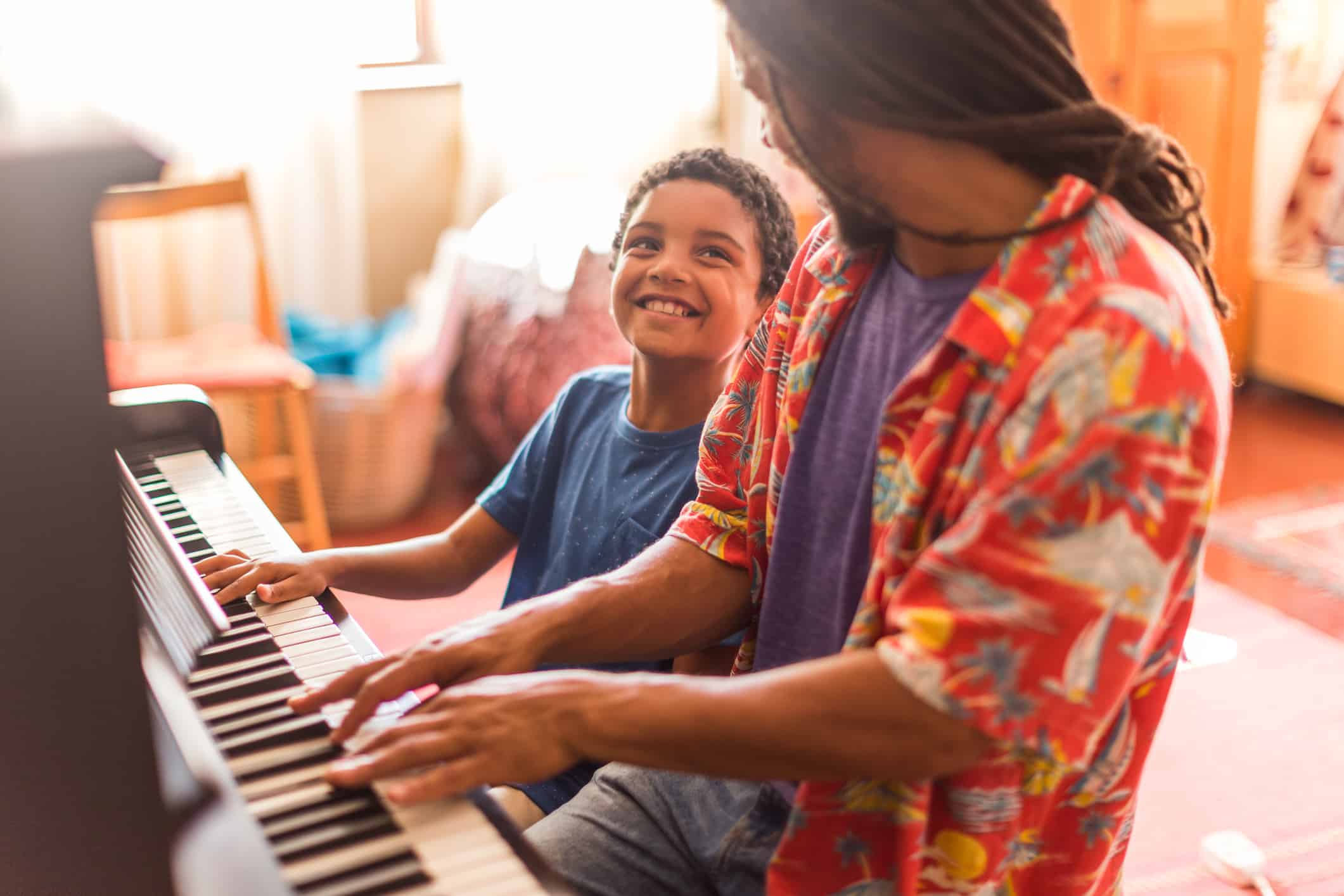 Father and son encouraging each other to piano playing in home